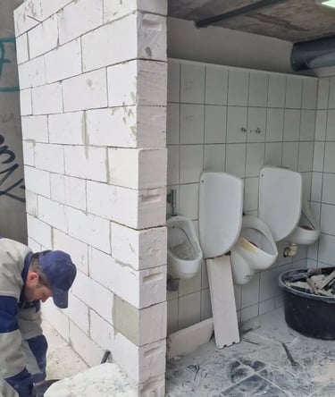 A construction worker builds an aerated concrete block wall during a public restroom renovation.