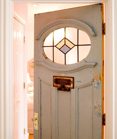 Vintage light blue interior door with an oval stained glass window and brass U.S. Mail slot.