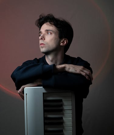 Arnavall debout appuyé sur un piano, de face