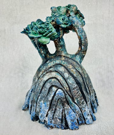 A ceramic plant-like sculpture glazed in green blue and brown tones