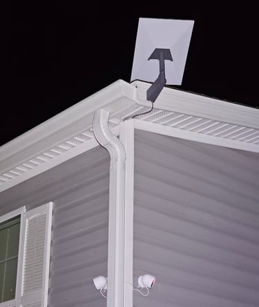 A rectangular Starlink satellite internet dish mounted on the roof of a house at night.