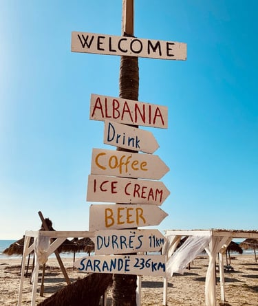 Handmade sign in Albania with arrow pointing to "coffee", "ice cream", "beer"