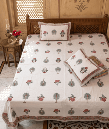 White cotton bedsheet with hand-block printed floral and palm tree motifs in a traditional Indian bedroom.