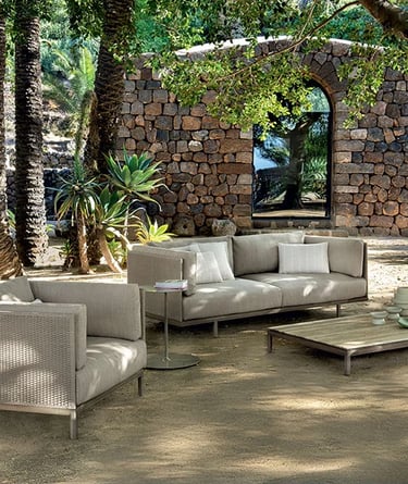 Garden seating with outdoor performance fabric, synthetic wicker, stone surfaces and natural materia