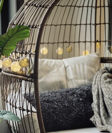 Cozy hanging lounge chair with soft cushions, warm lighting and natural textures for relaxed outdoor
