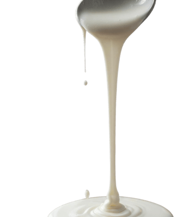 Thick white yogurt or cream pouring from a spoon onto a smooth surface against a white background.