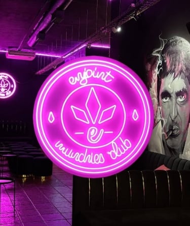 Logotipo Enjoint Munchies Club en neón rosa con diseño de hoja de cannabis y ambiente urbano