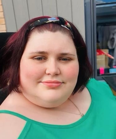 Katie in a green top sitting outside with hair in headband