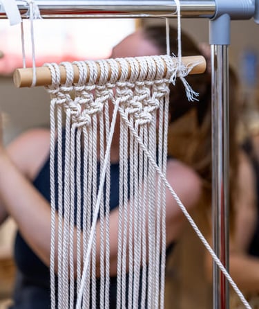 Nudos hechos con hilo blanco tejiendo sobre un palo de madera