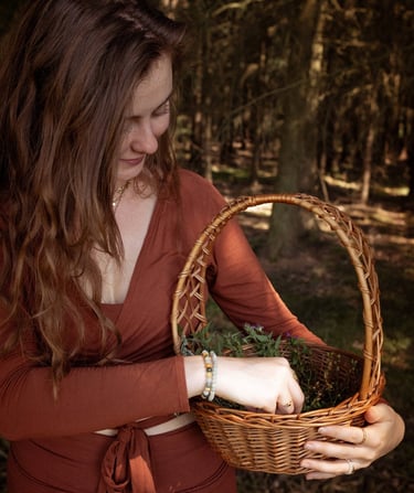 Eine Frau sammelt Kräuter in einem Korb, während sie in einem Wald steht.