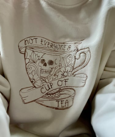 a white sweatshirt with a design thats embroidered saying not everyones cup of tea