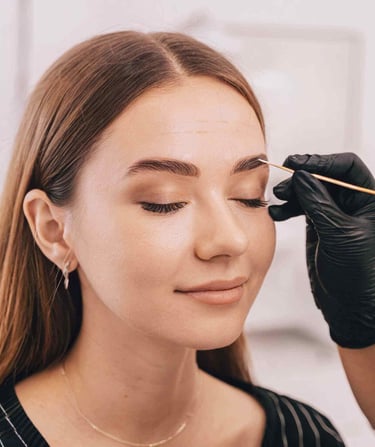 a woman is getting her eyebrows done by a professional makeup artist