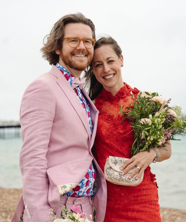 bride in red and groom in pink holding each other and smiling 