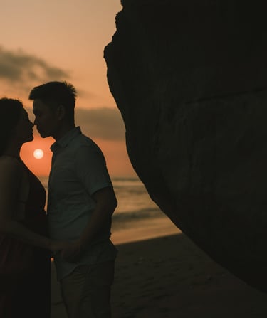 Silhouette of intimate couple kissing during sunset at Pantai Nyanyi Bali.