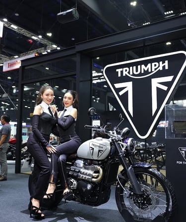 a woman standing next to a motorcycle with a woman sitting on it