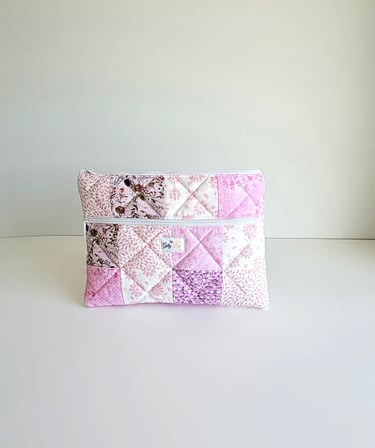Handmade pink quilted zipper pouch with floral patchwork patterns for makeup and accessories.