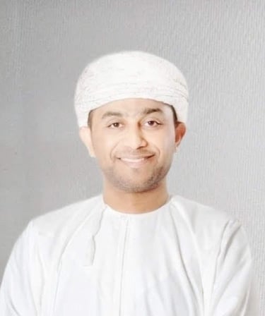 Portrait of a smiling Omani man, Khalil Al wearing a traditional white dishdasha and mussar turban.