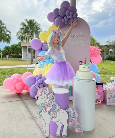 a girl in a unicorn costume stands next to a cake