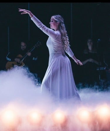 a woman in a white dress is dancing on stage at church