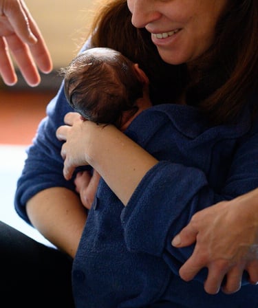 Une maman tenant son nouveau-né dans les bras après le Bain des Merveilles