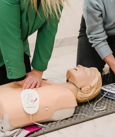 Two women administering CPR training on a CPR dummy in a training