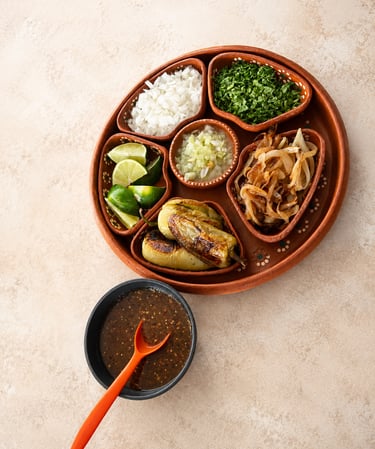 Guarniciones mexicanas frescas, salsa casera, cebolla, cilantro, limón, chiles toreados y cebolla.