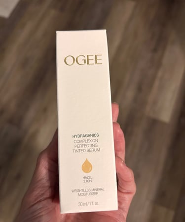 Hand holding Ogee Complexion Perfecting Tinted Serum box in shade Hazel 2.00N.