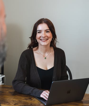 A Picture Of Abigail, the owner and founder of foundational wellness. Sitting at a desk, Smiling.
