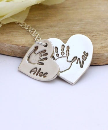Double descending silver heart necklace with the handprint and names of 2 children.