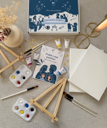 Kit créatif Paint Your Partner avec toiles, pinceaux, peintures et chevalets disposés sur une table.
