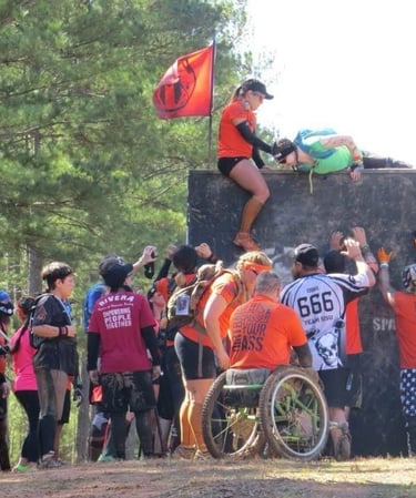 people helping other athletes over a wall at a spartan race