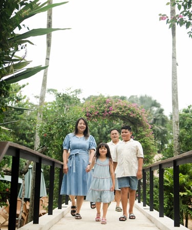 family walking together across a garden bridge during a natural family photography session at Movenpick Jimbaran Bali