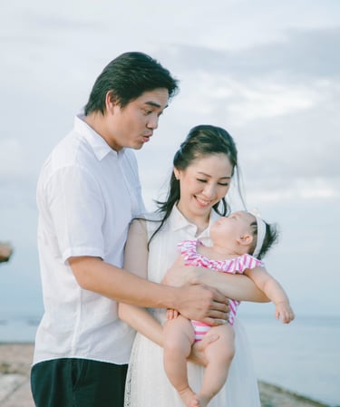 Parents holding baby with ocean view during family photography session at Sofitel Nusa Dua Bali