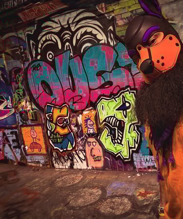 Man in a pup mask posing in front of a graffiti wall.