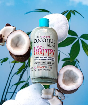 Treaclemoon Coconut Island shower gel styled with coconuts, foam and tropical leaves