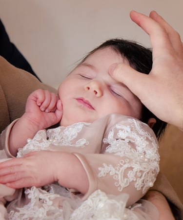 majka drži bebu u svojim rukama za vrijeme obreda krštenja