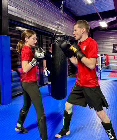 Entraînement de boxe : un homme et une jeune fille en garde, prêts à boxer