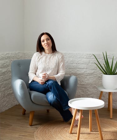 a woman sitting in a chair with a plant in front of her