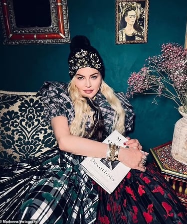 Madonna reading book in vintage-inspired room with a Frida Khalo painting.