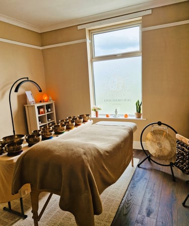 Treatment couch with singing bowls laid on a table, gong and seed chimes