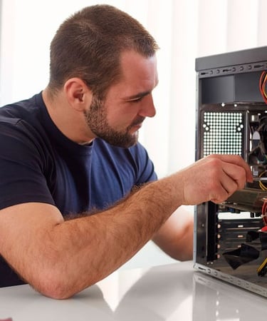 Professional technician repairing a desktop computer tower on a white desk in an office setting.