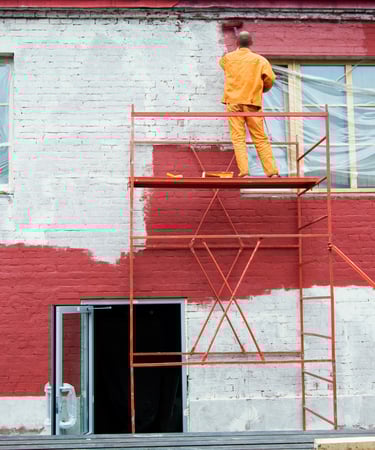 artisan qui peint une façade