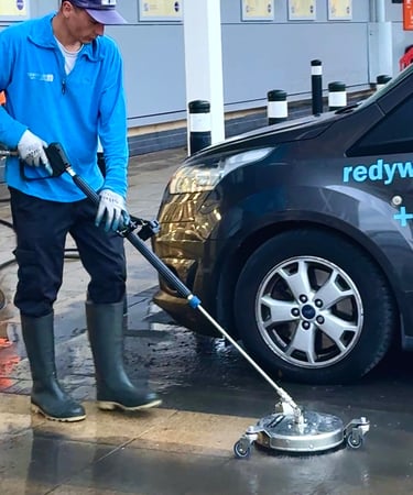 a man in a blue shirt is cleaning a patio using a pressure washing tool