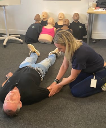 First aid learner practising CPR and casualty assessment skills on a person during training