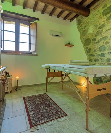 Sala relax dell'agriturismo con panorama su Assisi e muro di pietra a vista