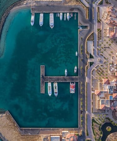 Aerial view of a luxury coastal resort marina with yachts anchored in turquoise water.
