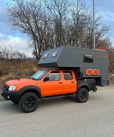 un vehículo pick up naranja con cabina camper