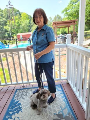a woman standing on a porch with a dog on a rug