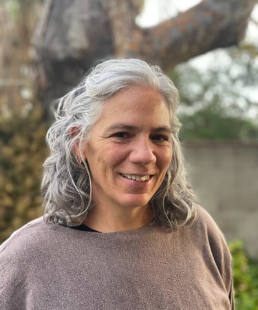 Woman with grey hair and brown sweater