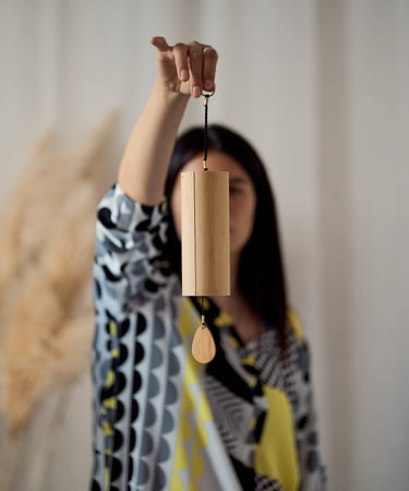 a woman holding a wooden wind chime